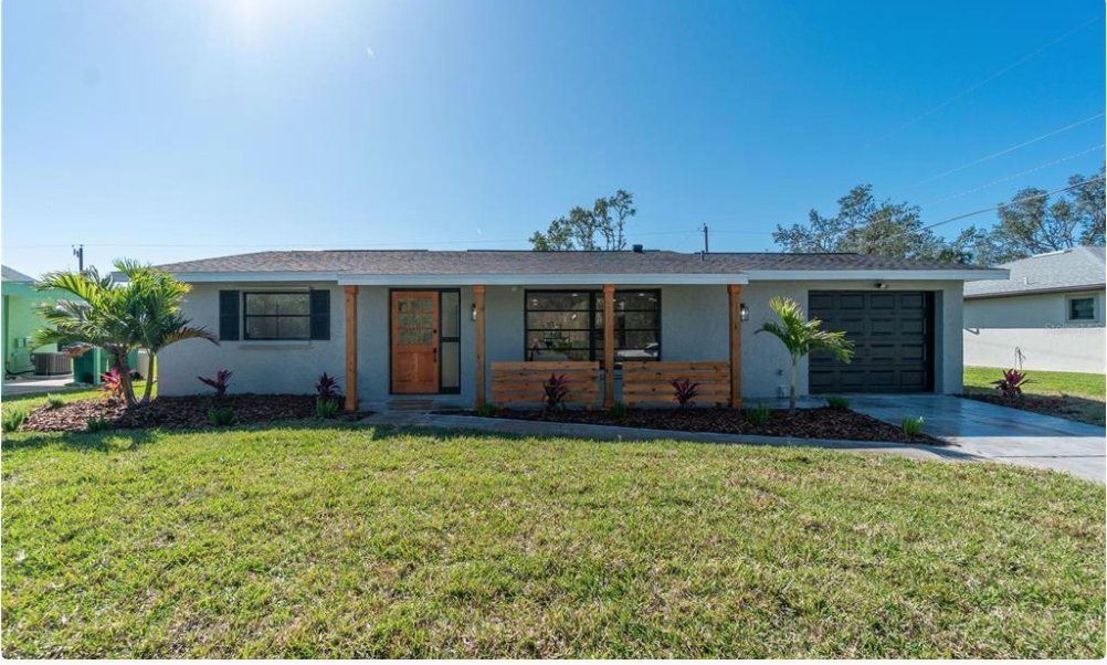 After: fully renovated home exterior with new roof, fresh stucco, wood porch posts, and landscaping